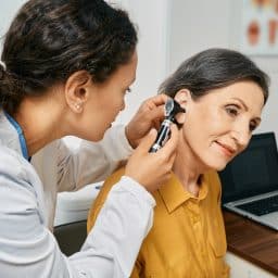 Senior woman having her ears examine by a doctor to check for hearing loss.