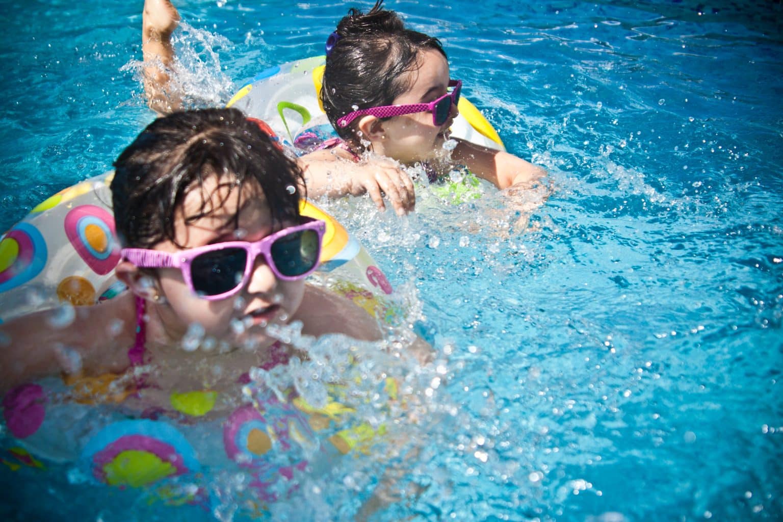 Young girls swimming and having fun in an outdoor pool.