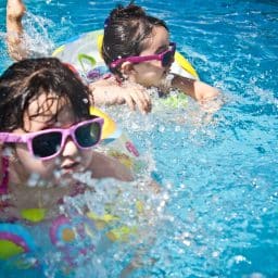 Young girls swimming and having fun in an outdoor pool.