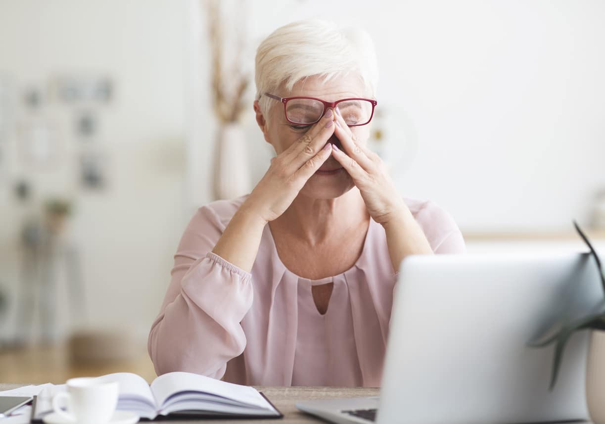 Senior woman exhausted while working at her laptop.