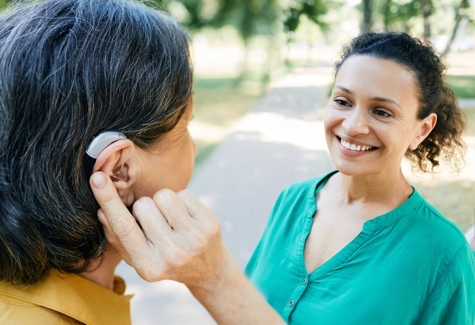 Woman with hearing aid chats with her friend outside.